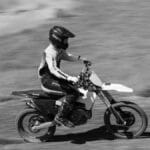 Dynamic black and white photo of a motocross rider racing on a dirt track in Pennsylvania.