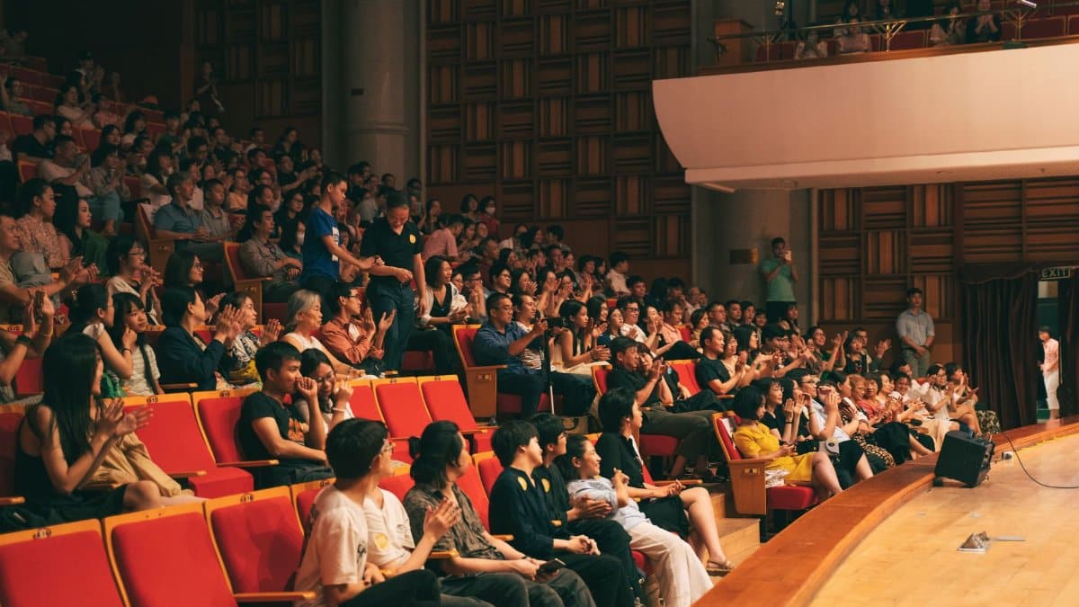 A lively audience applauding in a spacious concert hall, creating energy and excitement.