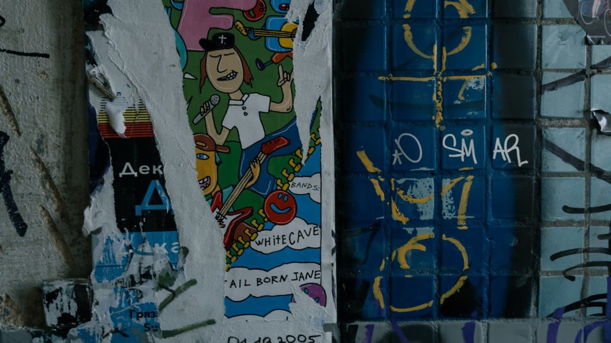 Vibrant street art poster on a graffiti-covered urban wall, depicting musical themes and abstract designs.
