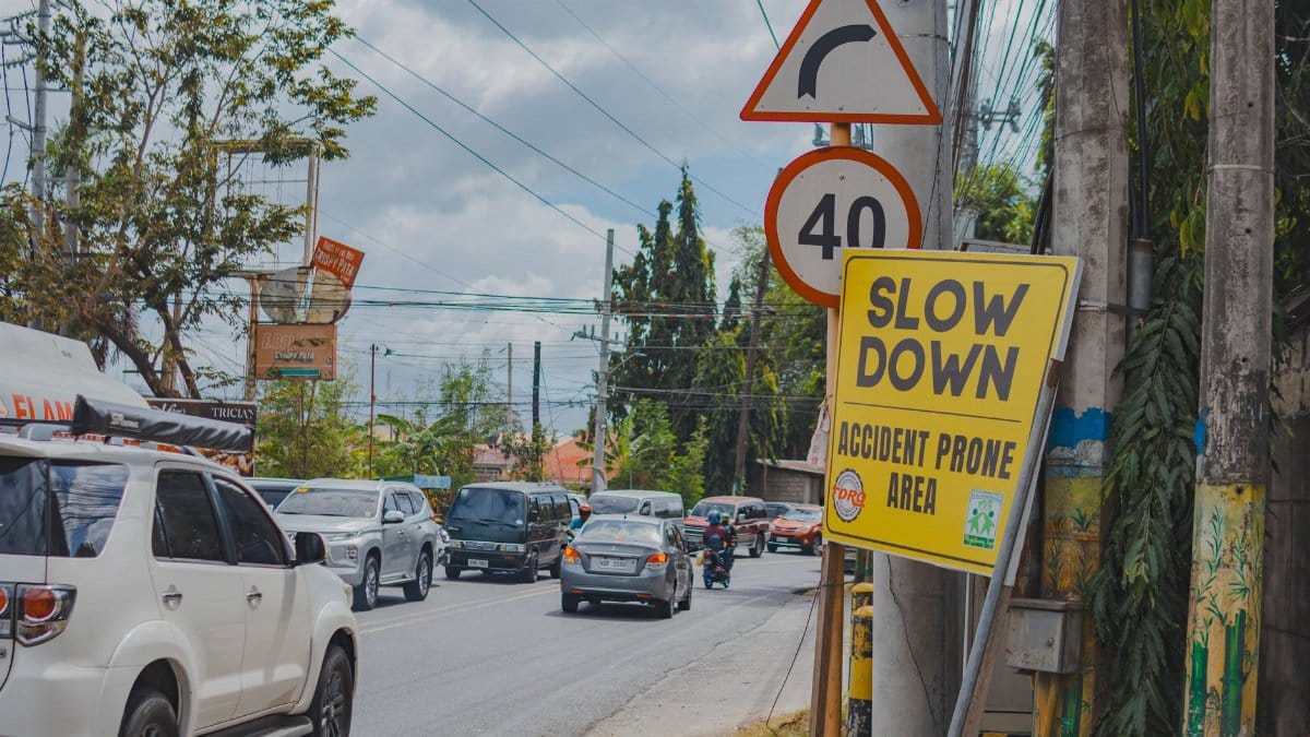 Heavy urban traffic on a city street with visible road signs. Vehicles and road safety signs dominate the scene.