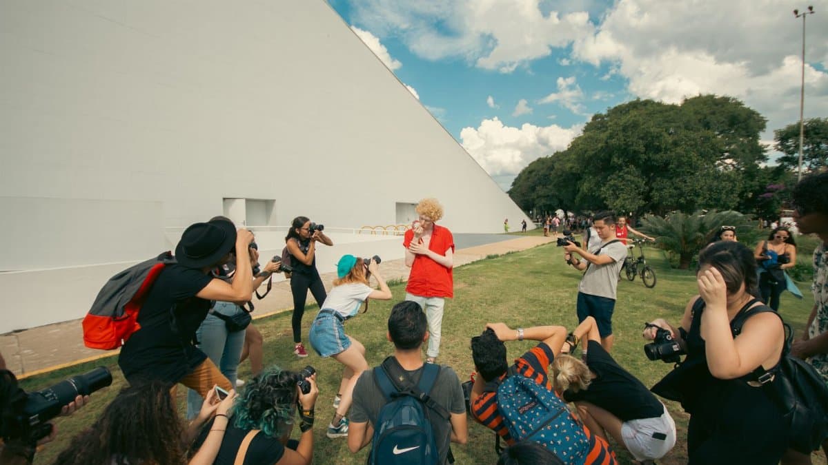 Photographers taking pictures of a performance outside a modern building.