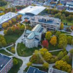 Drone shot capturing a scenic university campus with vibrant fall foliage.