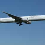 Air New Zealand Boeing 777 airliner flying against a clear blue sky, showcasing aviation travel.