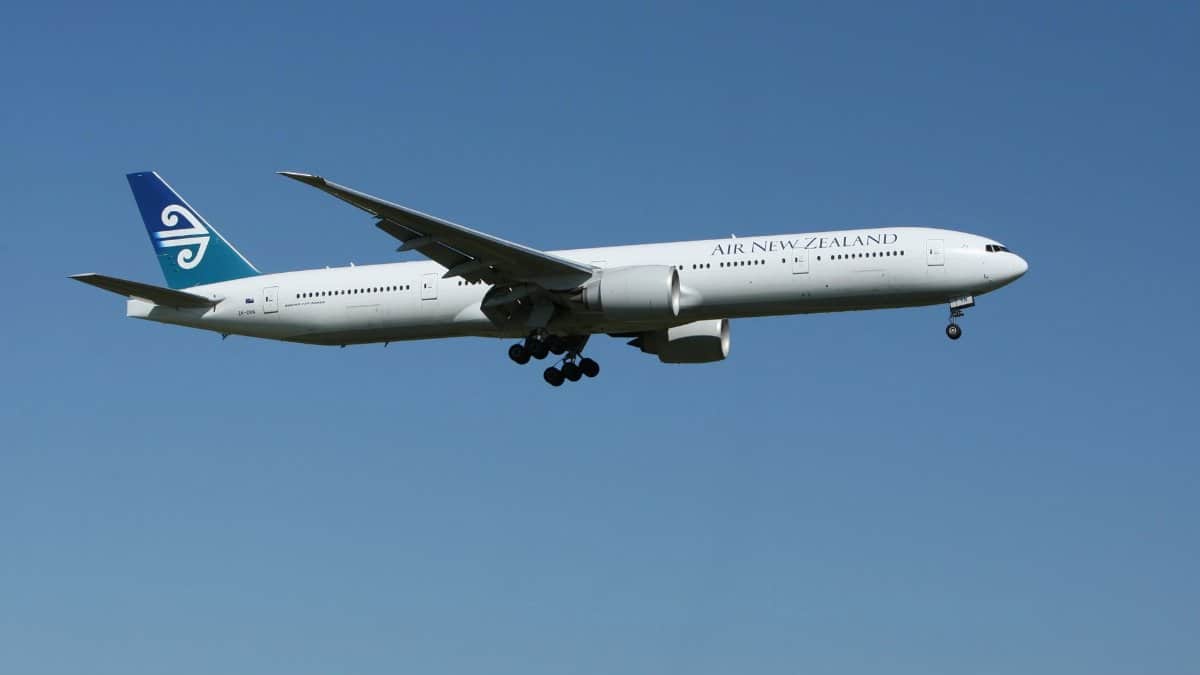 Air New Zealand Boeing 777 airliner flying against a clear blue sky, showcasing aviation travel.