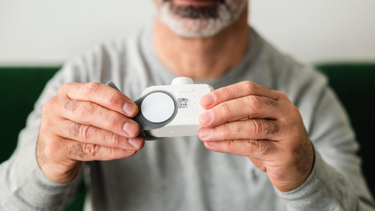A close-up of a man using a handheld air quality analyzer, focusing on health and technology.