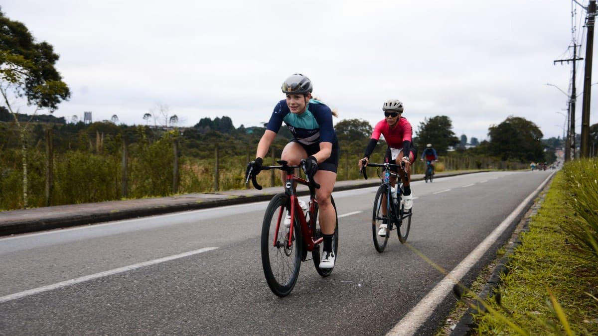 Athletic cyclists in vibrant gear racing on an open road in Quatro Barras, Brazil.