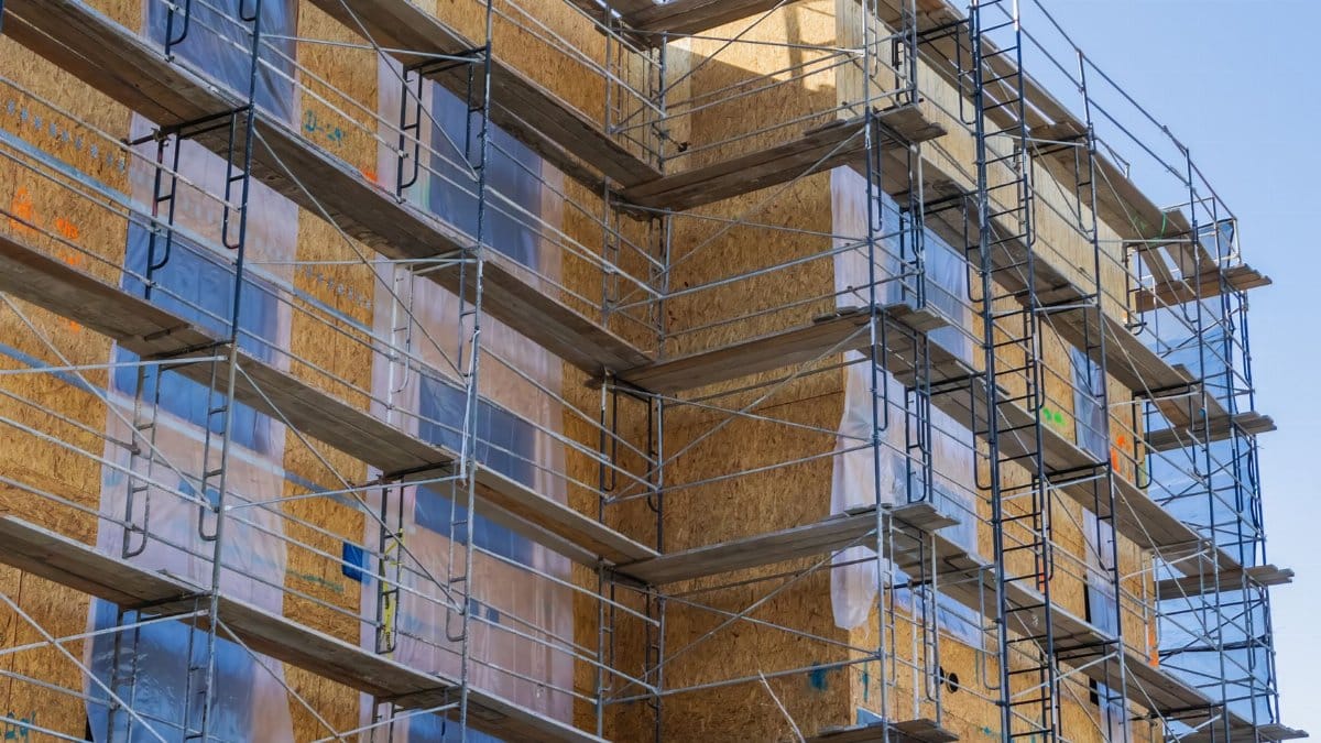 A high-rise building with scaffolding for construction and repair work under a clear sky.