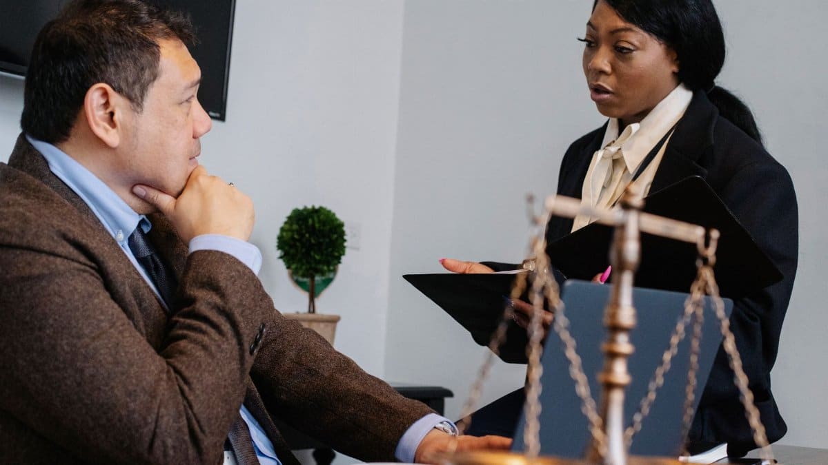 Side view of pensive diverse colleagues in formal clothes sitting at table and discussing details of project at work