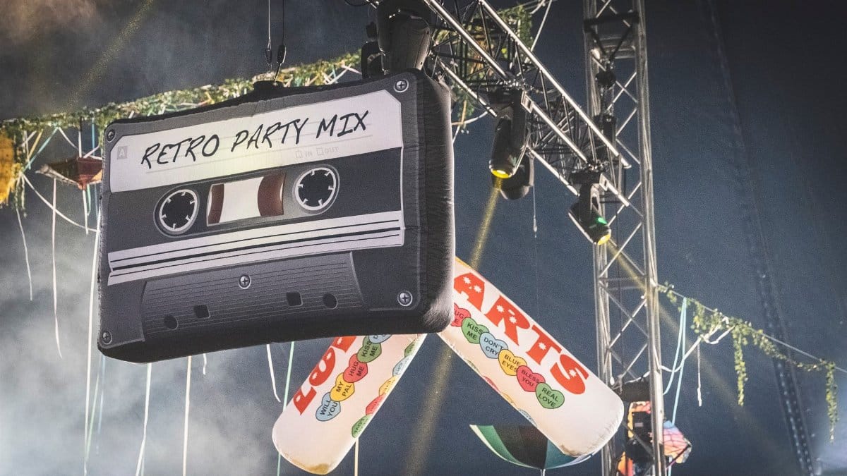 Hanging retro cassette and Love Hearts decorations at a vibrant music festival stage.
