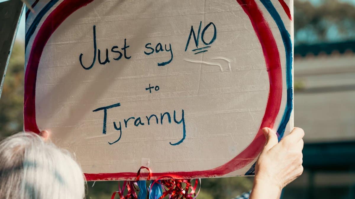 Protester holding a sign reading 'Just say NO to Tyranny'. Advocacy scene outdoors.
