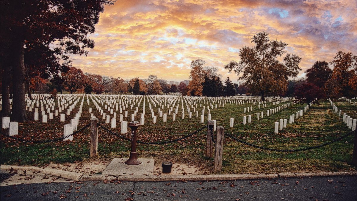 Serene view of Arlington National Cemetery under a vibrant autumn sunrise sky.