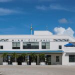 Front view of Miami City Hall with palm trees under a clear blue sky.