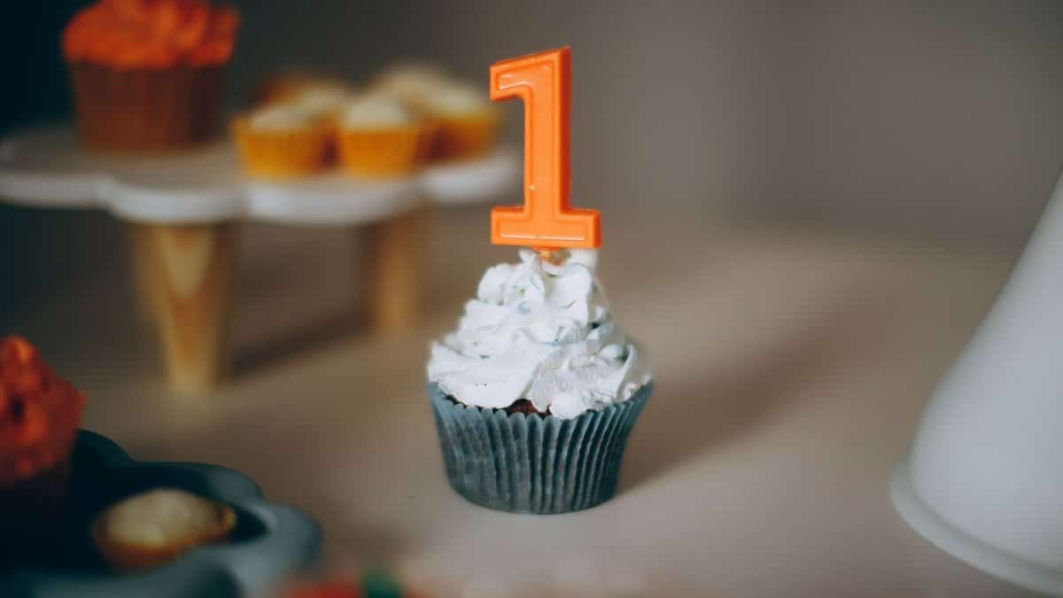 Blue cupcake with white frosting and orange number 1 candle, ideal for a first birthday celebration.