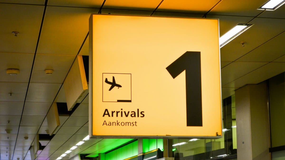 Bright arrivals sign with airplane symbol in an airport terminal.