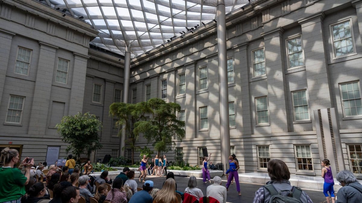 Modern dance performance in atrium at Washington DC Museum with audience.