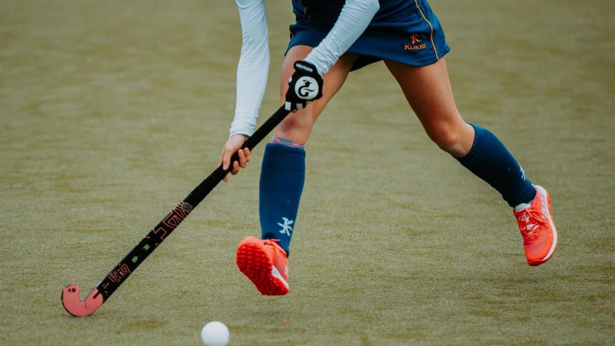 Action shot of an athlete playing field hockey on a turf field.