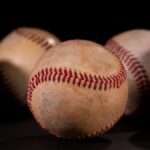 Detailed close-up of vintage baseballs on a dark black background, showcasing texture and stitching.