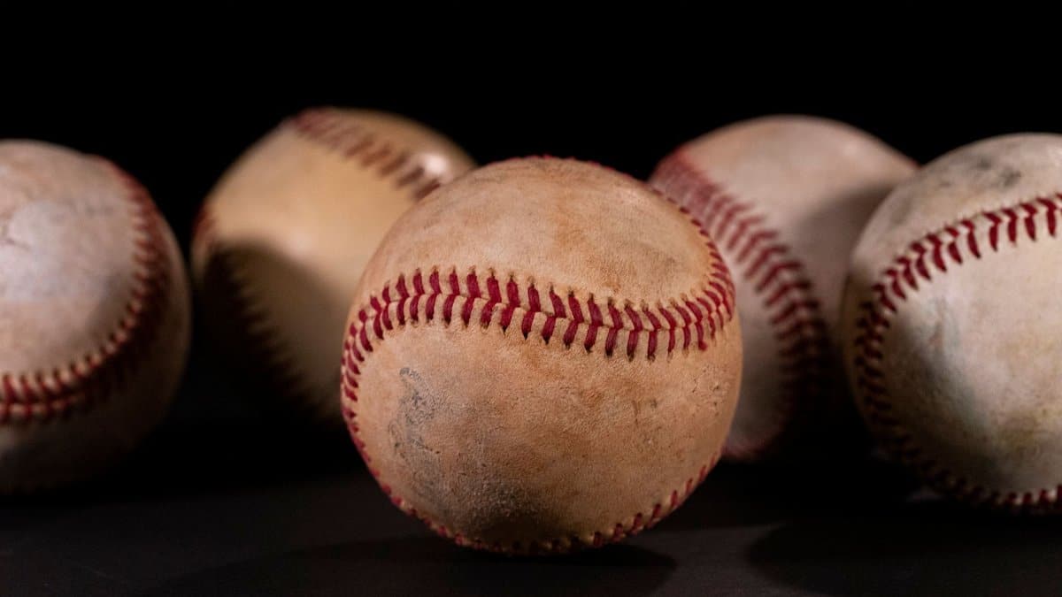 Detailed close-up of vintage baseballs on a dark black background, showcasing texture and stitching.