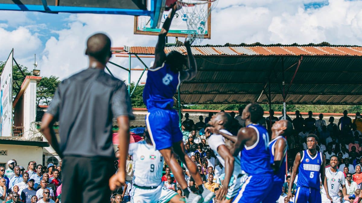 Intense basketball game with players in action on an outdoor court, drawing a lively crowd.