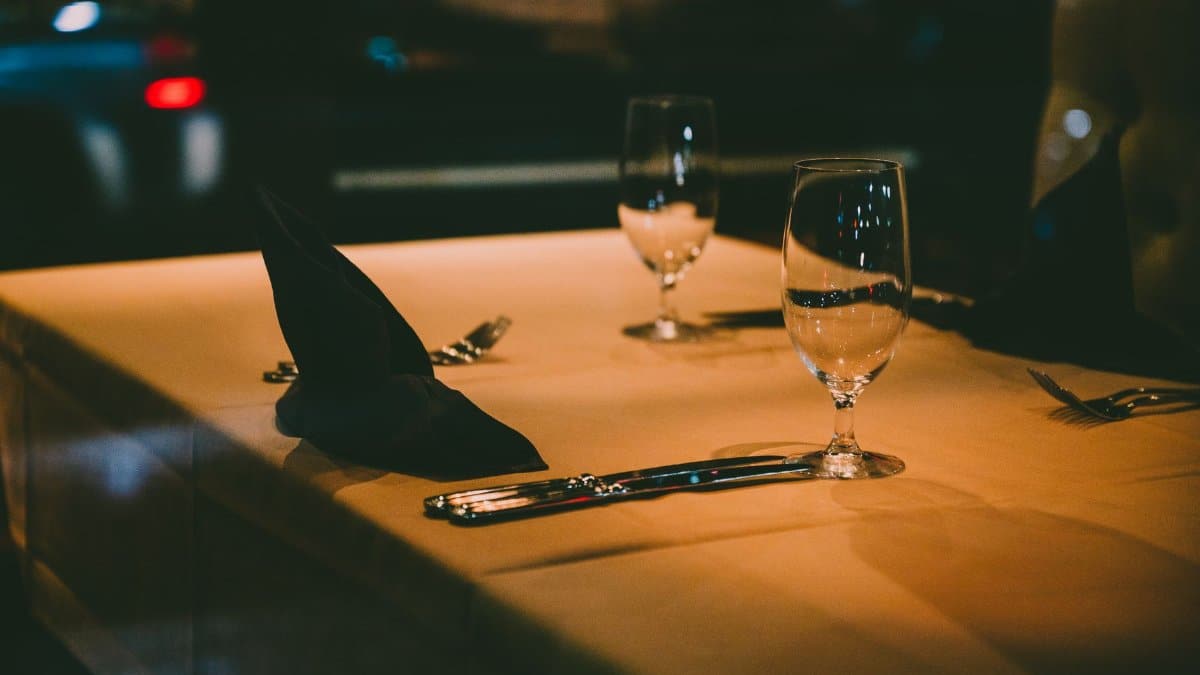 Elegant restaurant table setting with cutlery and wine glasses under warm lighting.