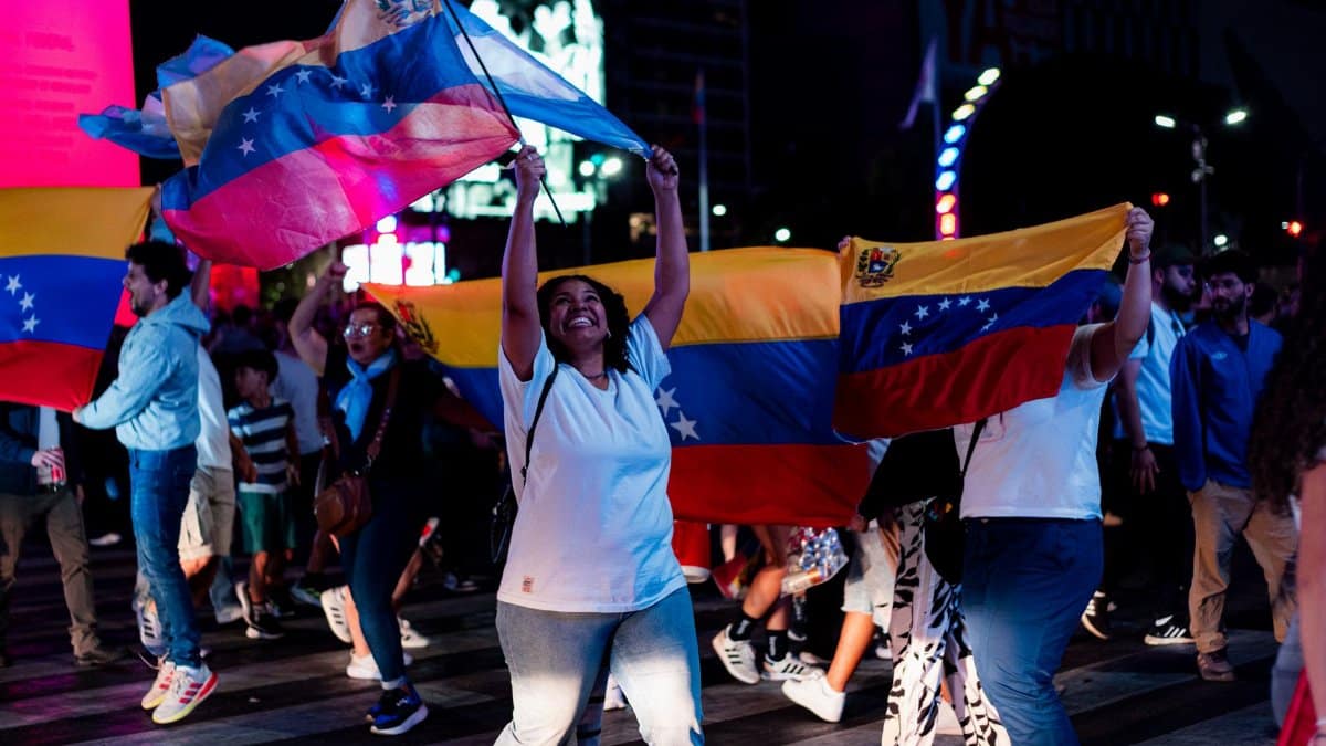 A vibrant street celebration with Venezuelan flags and joyful people in Buenos Aires at night.