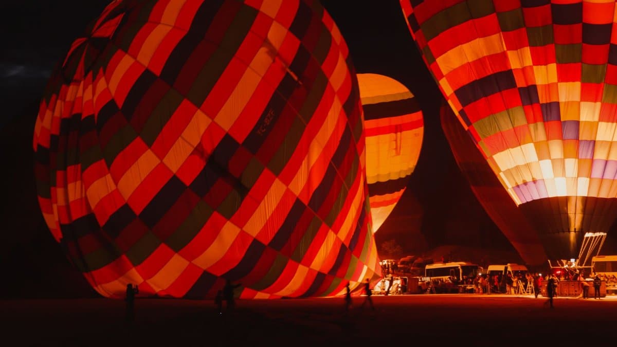 Colorful hot air balloons illuminated at night, ready for ascension during a festival.