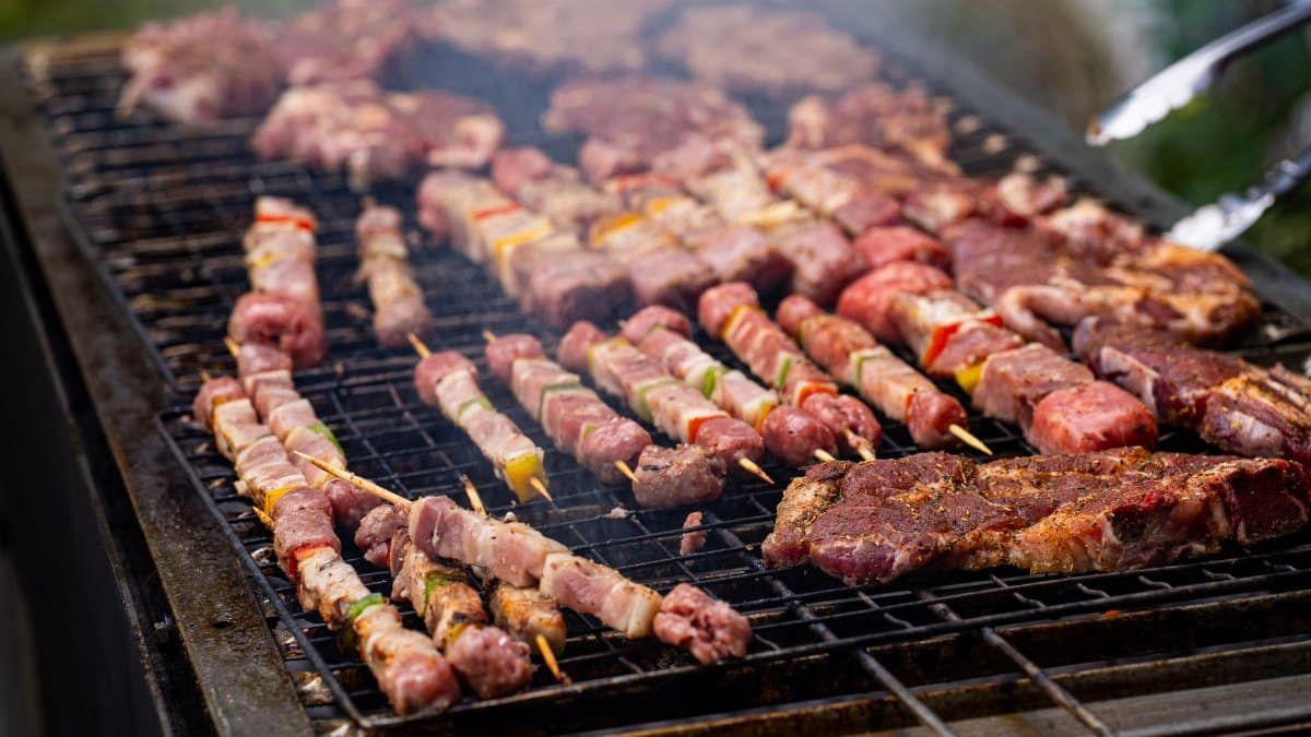 Close-up of various meats and skewers grilling on a barbecue, perfect for outdoor gatherings.