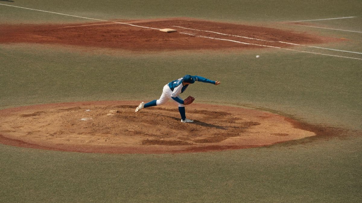 A skilled baseball pitcher delivers a pitch on a sunlit field in Tokyo, Japan. Captured in dynamic motion.
