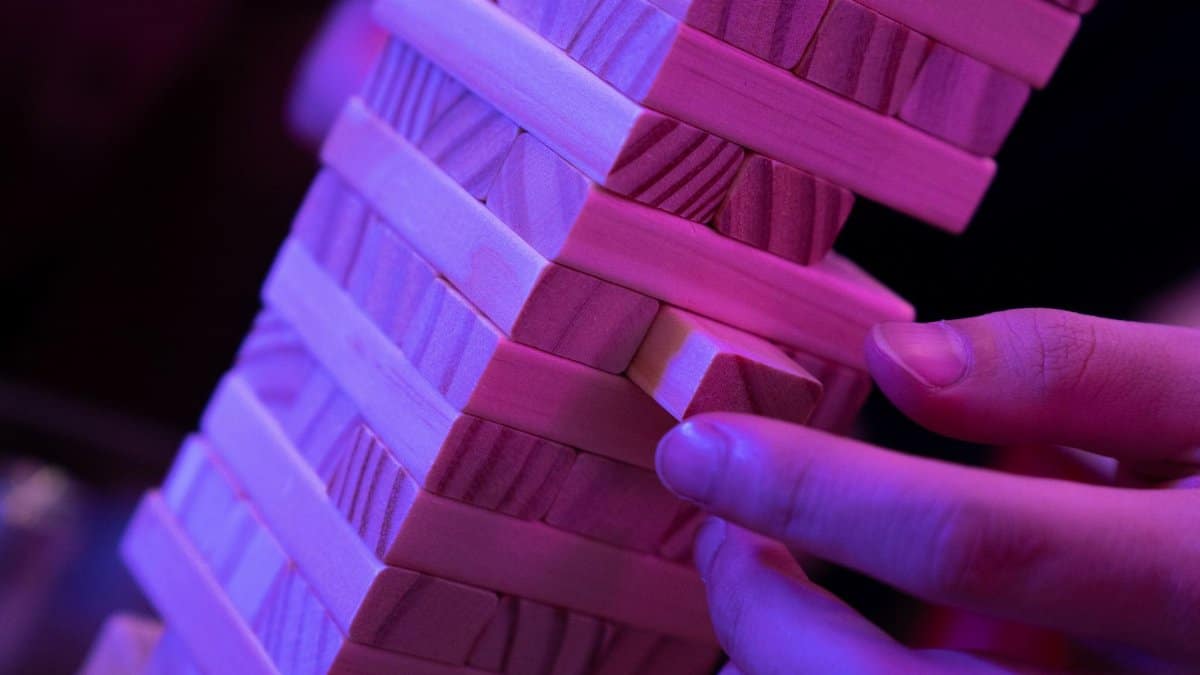 Detailed close-up of hands skillfully playing a wooden block stacking game under colored lights.