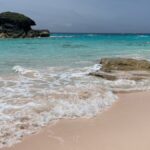 A serene sandy beach in Bermuda featuring turquoise waters and unique rock formations.