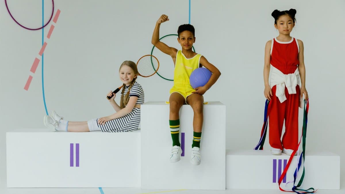 Children celebrating with sports equipment on a podium. Diversity and joy captured indoors.