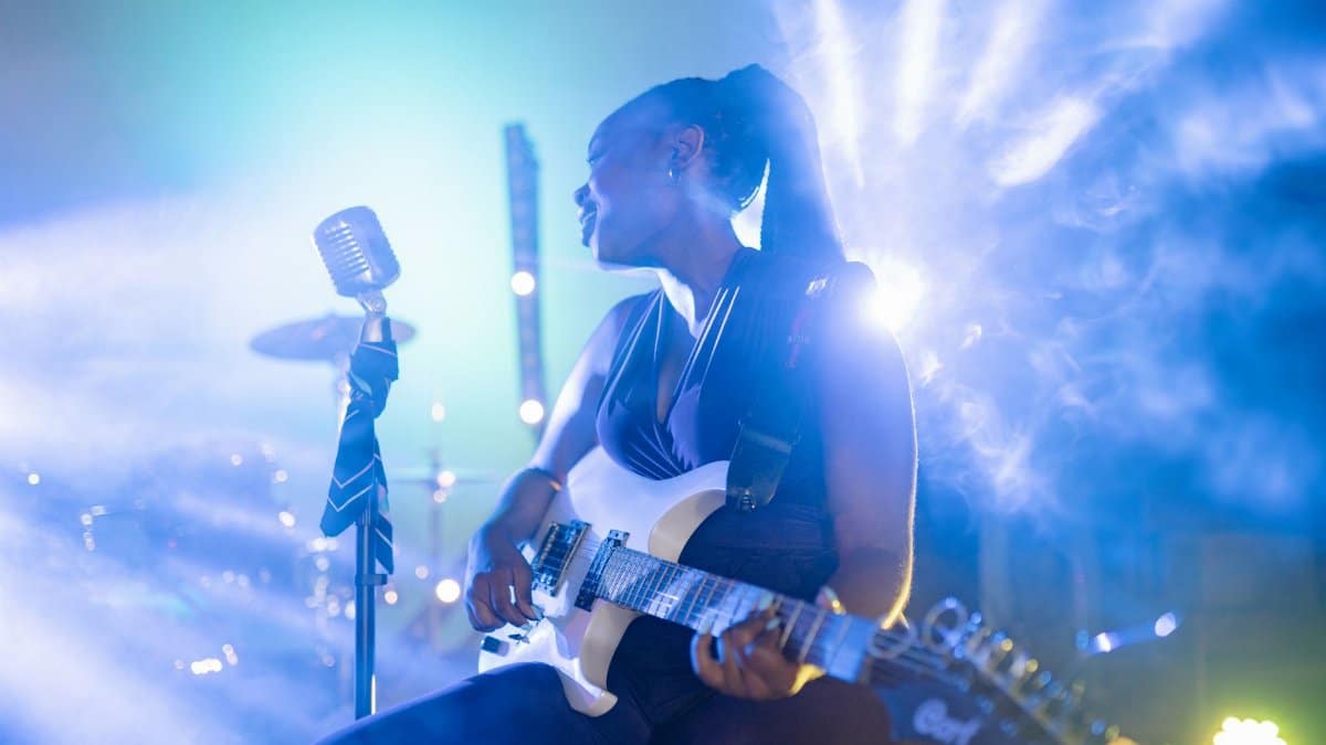 Musician playing electric guitar under dramatic stage lights, exuding energy and passion.