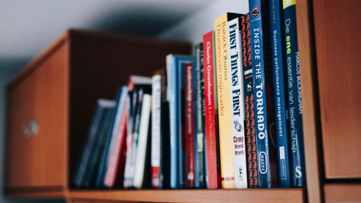 A variety of books neatly arranged on a wooden bookshelf.