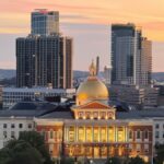 A breathtaking view of Boston's skyline with the Massachusetts State House at sunset, showcasing its iconic golden dome.