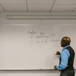 Instructor writing exam rules on a whiteboard in a college classroom.