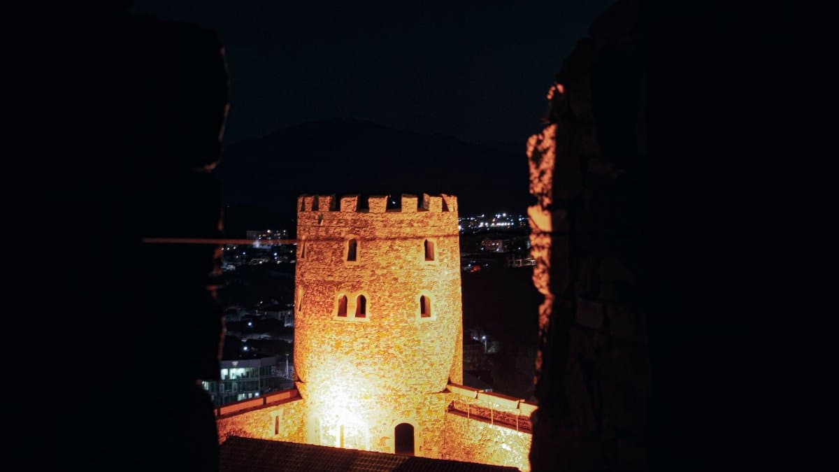 A glowing castle tower captured at night, providing a historical ambiance.
