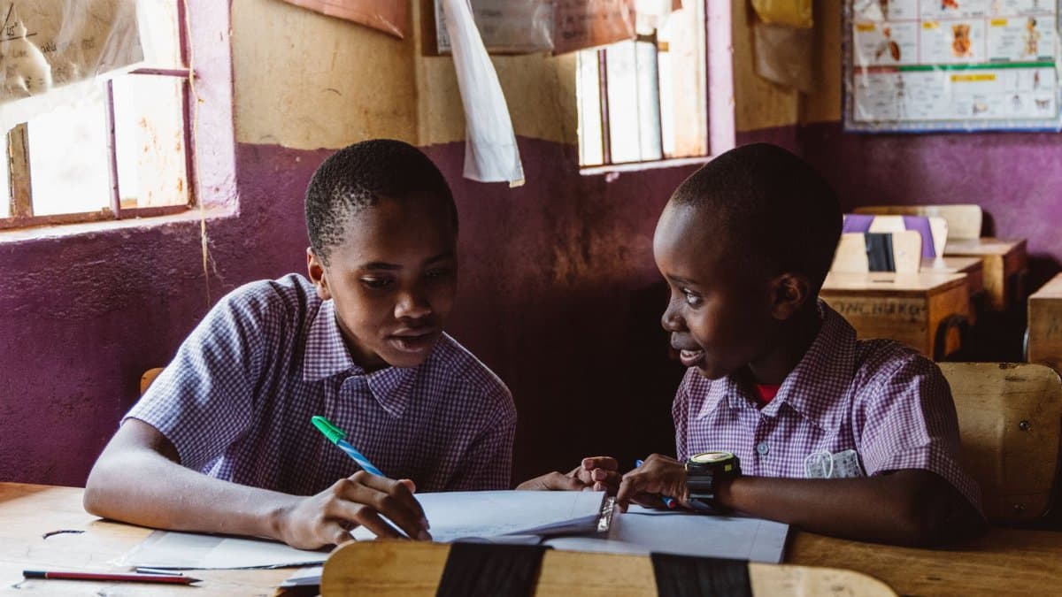 Two boys collaborating on schoolwork in a classroom setting with natural light.