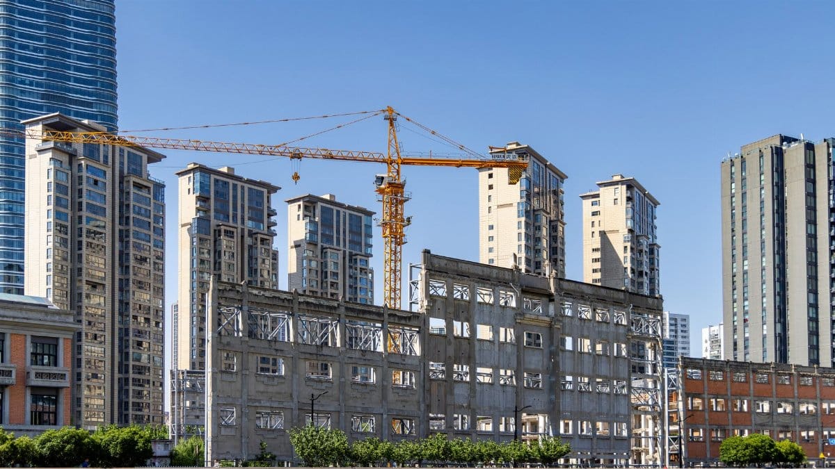 Urban redevelopment featuring cranes and high-rise buildings under a clear blue sky.