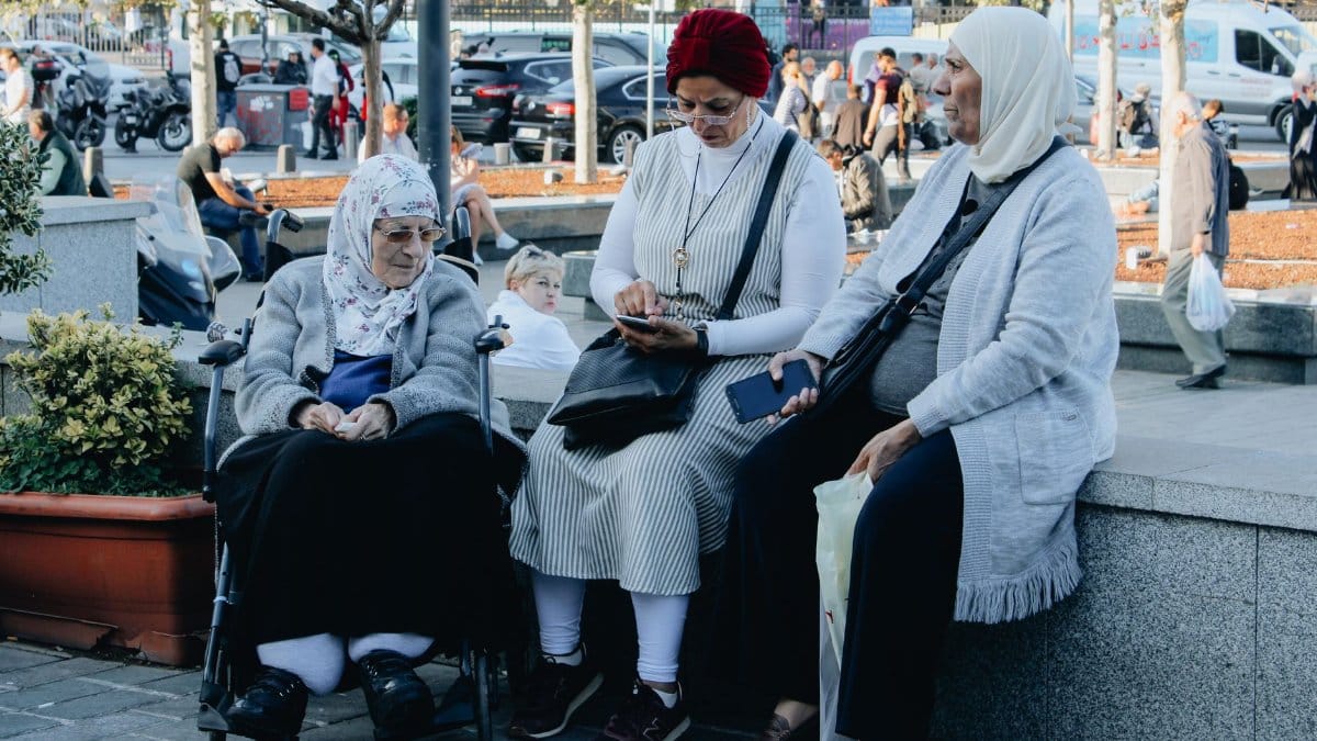 Elderly women in headscarves sitting on a street in Istanbul, engaged in conversation.