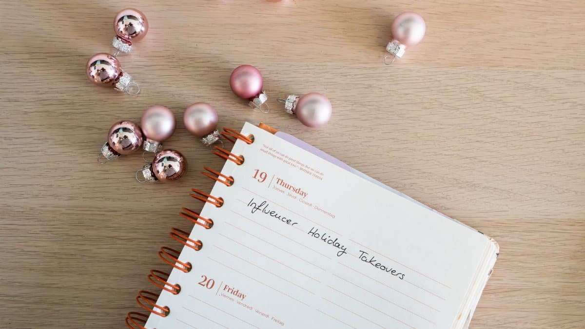 Open planner with Christmas baubles on wooden surface. Perfect for holiday planning themes.