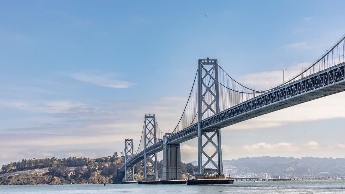 A stunning view of the San Francisco Bay Bridge extending over calm waters under a bright blue sky.
