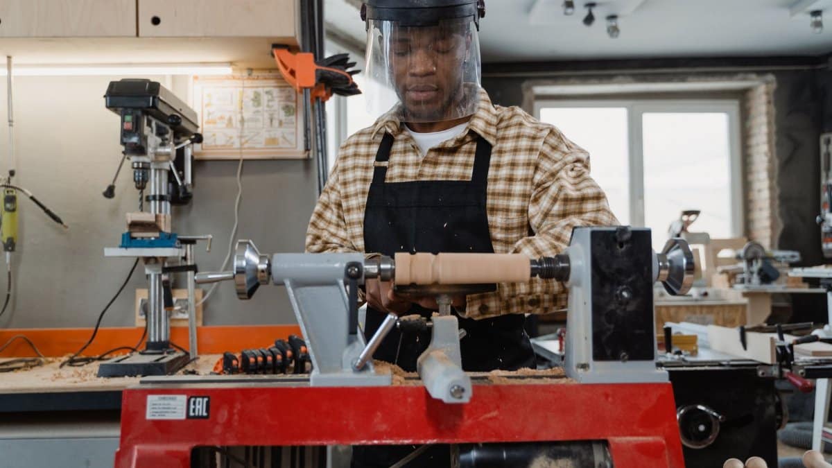 A professional craftsman using a wood lathe in a workshop, focusing on precise woodworking skills.