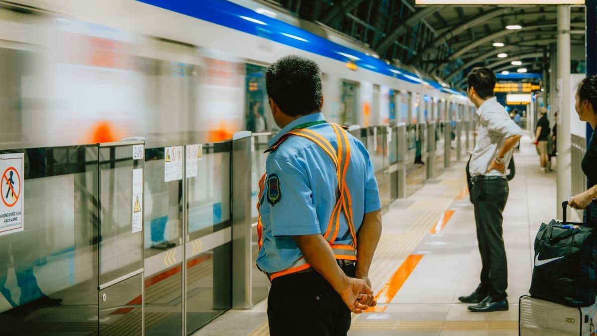 Security guard overseeing platform at Vietnam metro station. Train arriving swiftly.