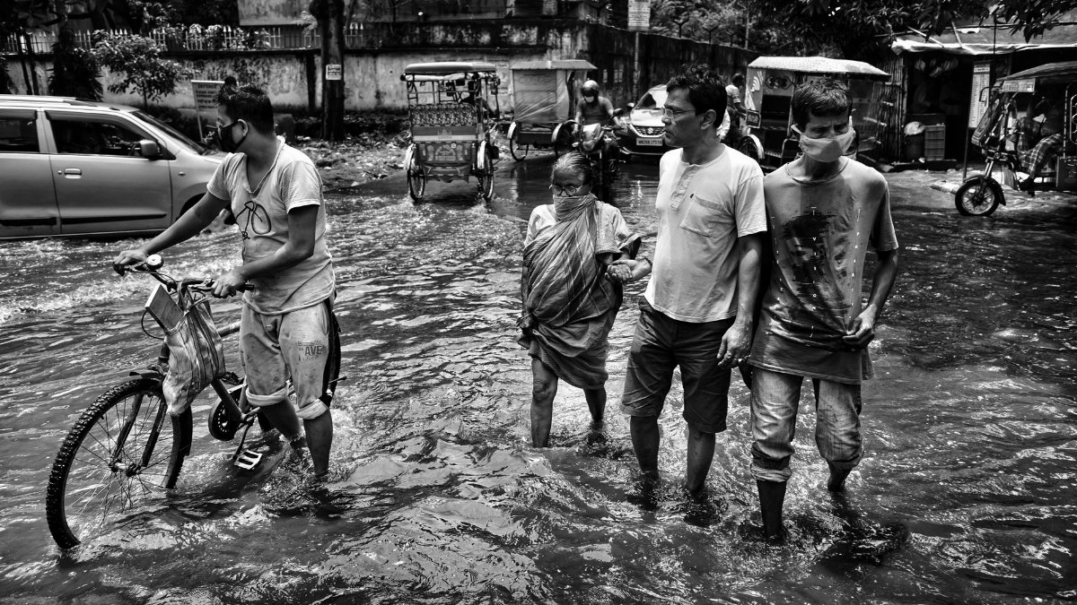 People navigate flooded Kolkata streets, showcasing the challenges of urban life during monsoon.