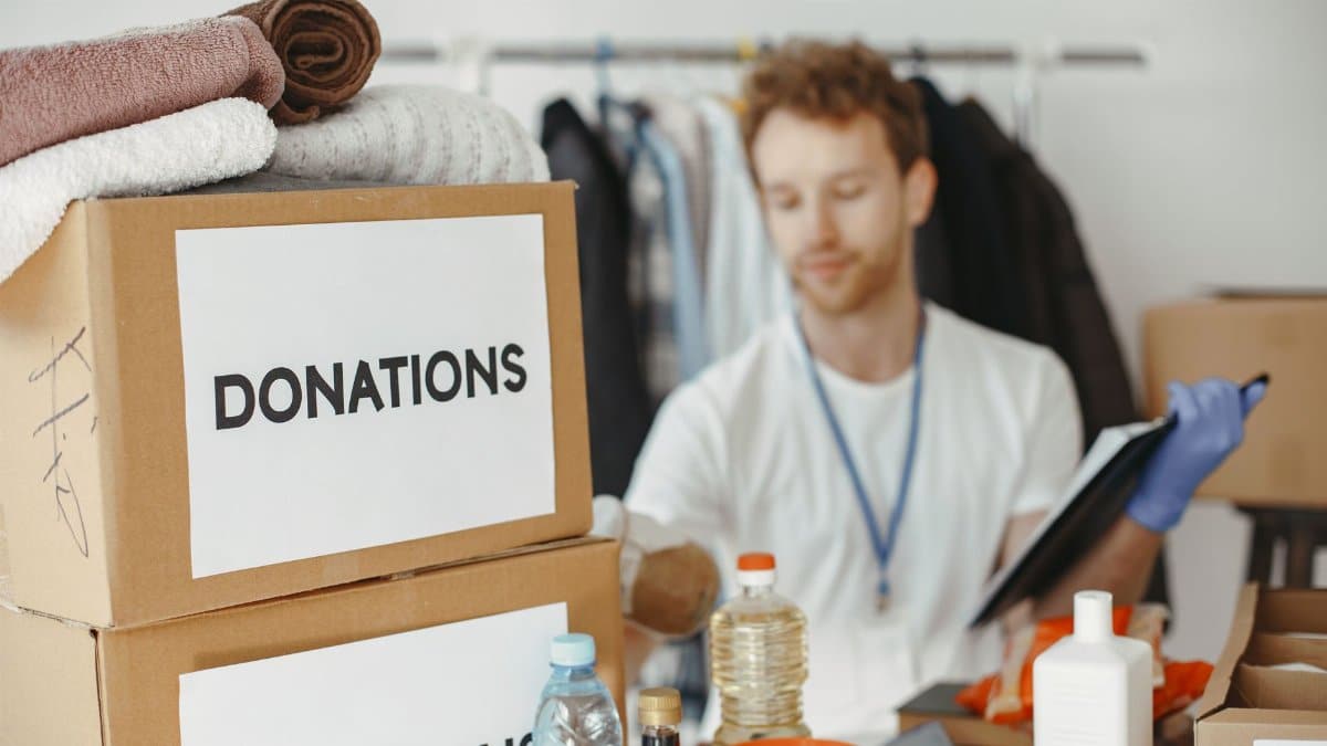 Volunteer organizing donation boxes with clothes and supplies for charity.