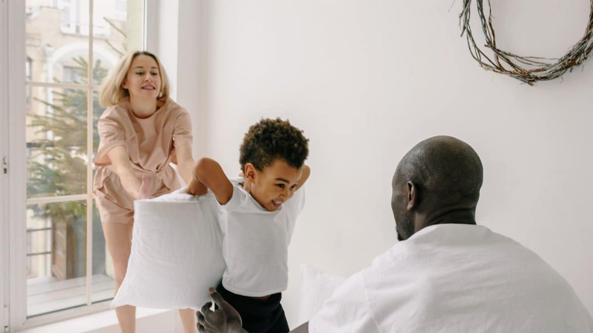 Joyful family having a playful pillow fight indoors, capturing happiness and bonding.