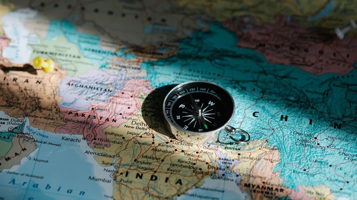 Close-up image of compass on a world map highlighting travel direction and exploration.