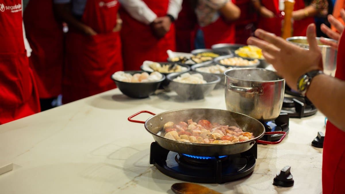 Participants learn cooking skills in a vibrant class setting, engaging with hands-on food preparation.