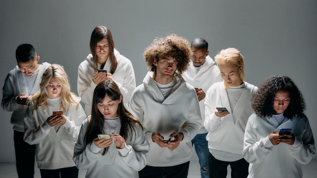 A group of diverse young adults focused on smartphones, symbolizing modern technology and digital connection.