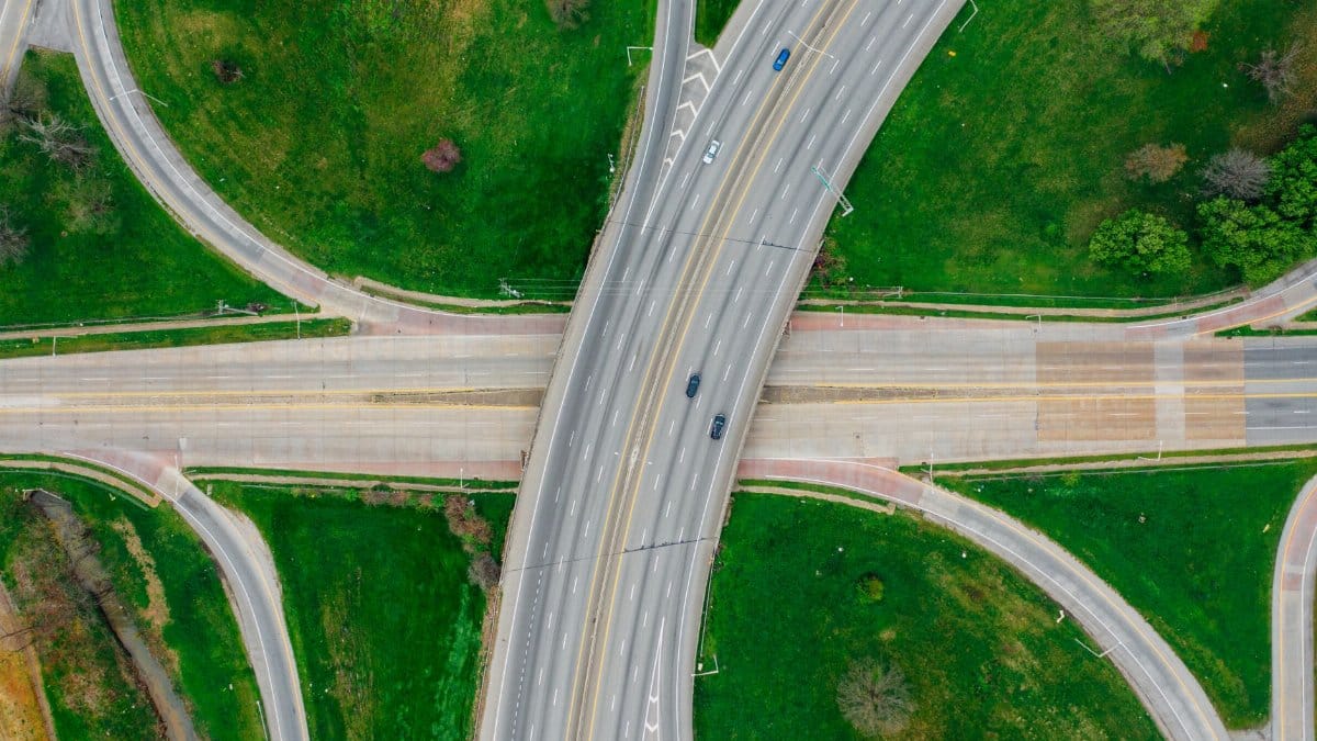 A striking aerial view of a highway intersection with green surroundings, showcasing urban infrastructure.